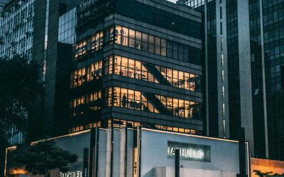 Night view of a city block with illuminated store, modern architecture, and cloudy sky.